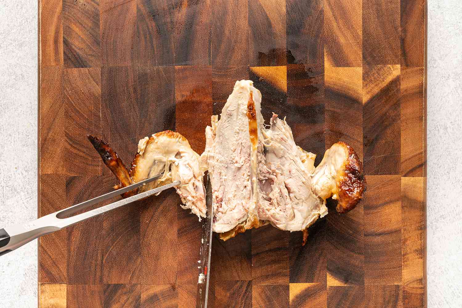 يتم نحت الدجاج المشوي على لوح التقطيع ، ويتم فصل الجناح عن عظم الصدر بالسكين